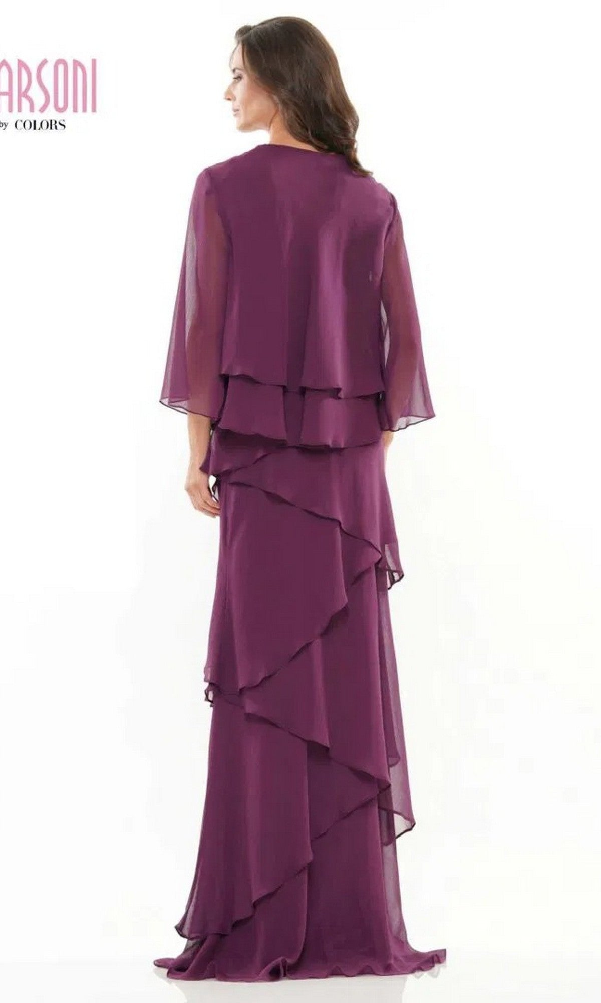 A woman in the Long Formal Dress: Marsoni M309, a floor-length purple chiffon gown with a matching sheer cape, stands facing away from the camera against a plain white background.
